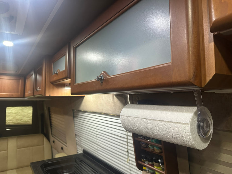 RV rental kitchen: wooden cabinets with frosted glass, paper towel holder, and spice rack for compact travel.