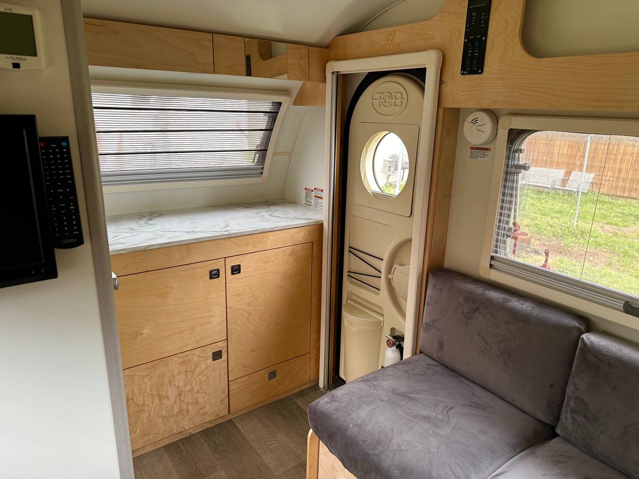 and bright windows.|Cozy RV rental interior features a versatile convertible bed