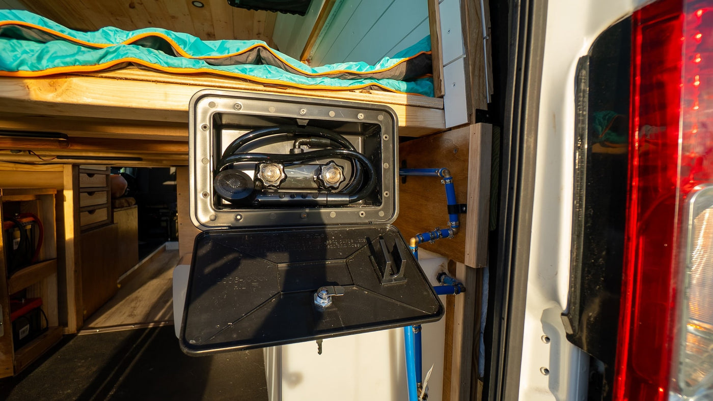 RV rental camper van features an outdoor shower unit with mixer, hose, and blue PEX plumbing for convenience. — photo 12