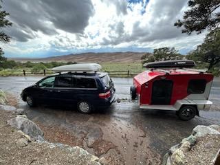 a compact travel trailer with a rooftop carrier & spare tire
