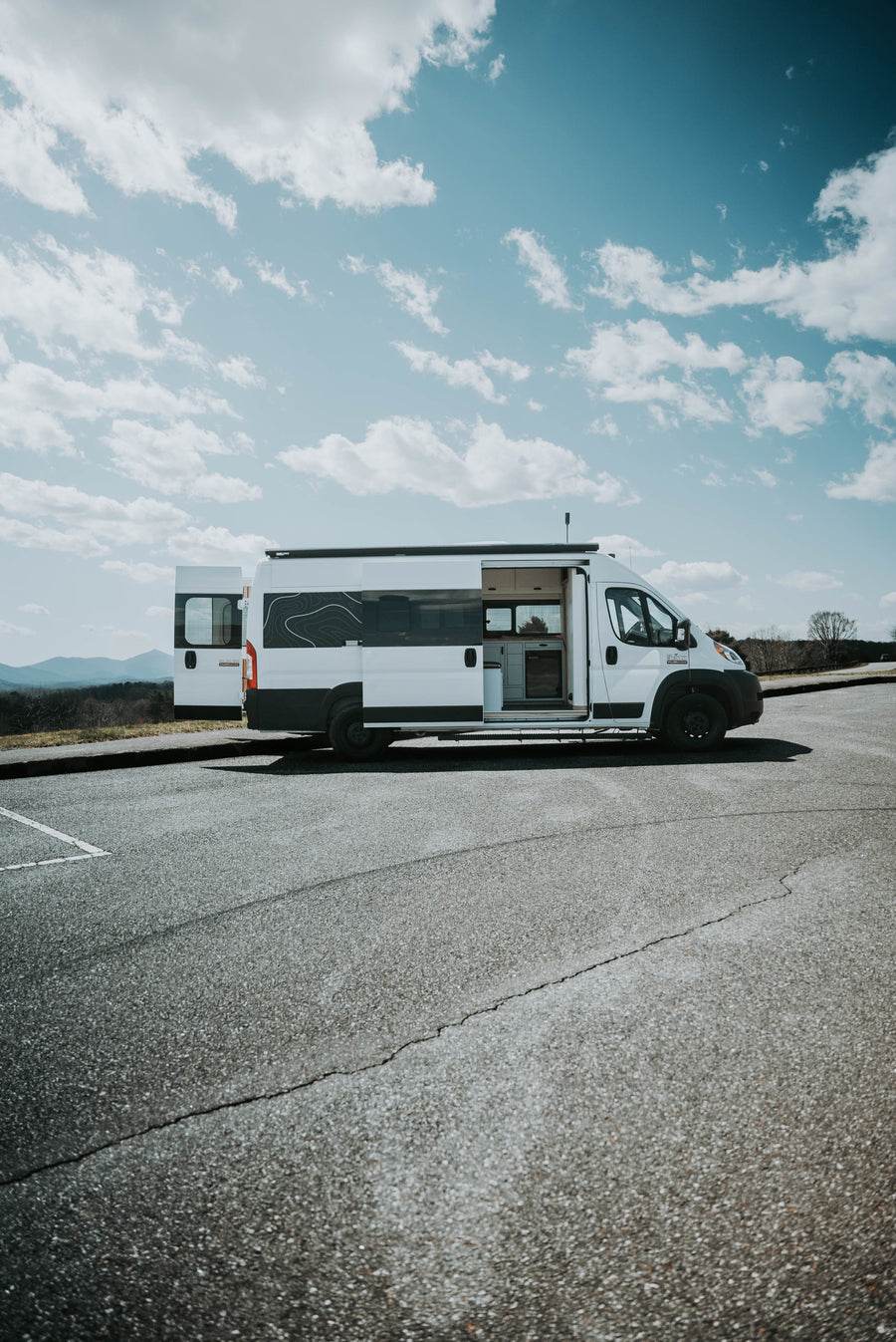White RV rental camper van parked at a scenic mountain overlook with doors open
