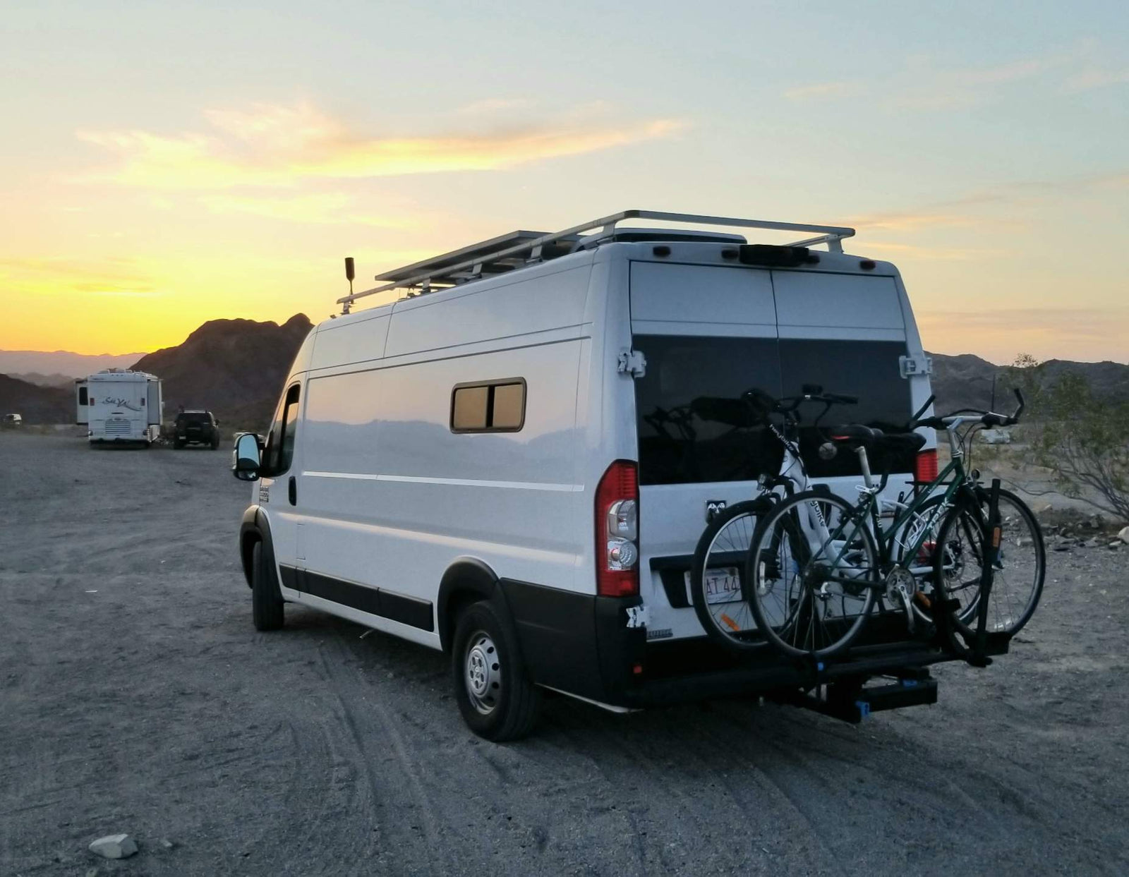 A white RV rental camper van with two bicycles on a rear rack