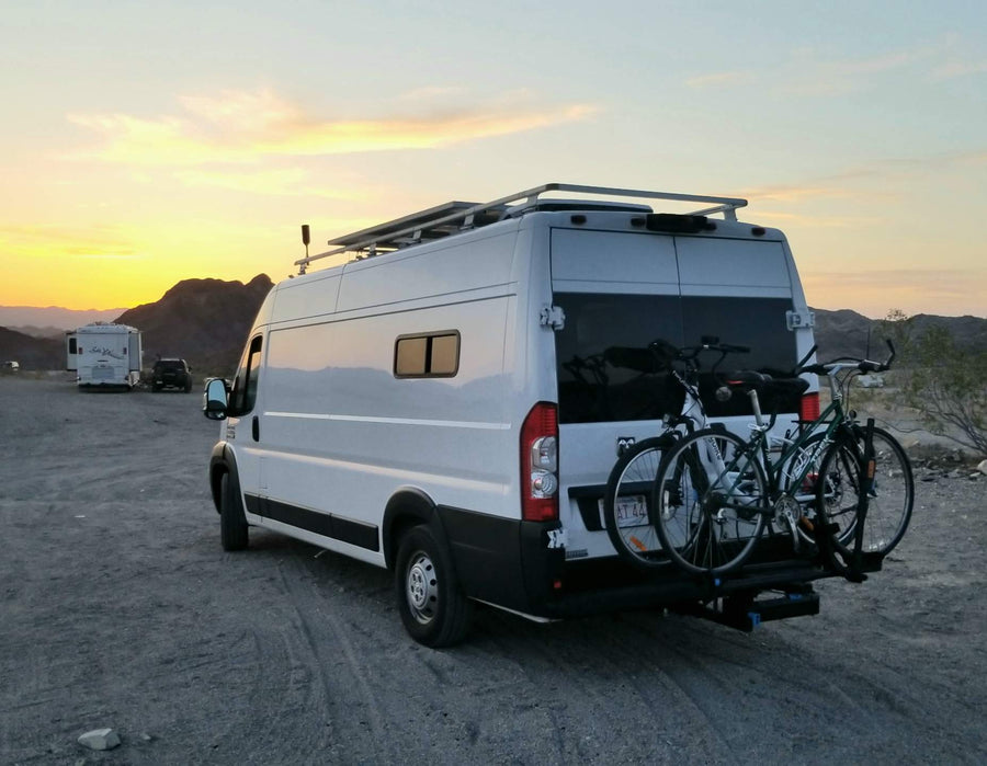 A white RV rental camper van with two bicycles on a rear rack