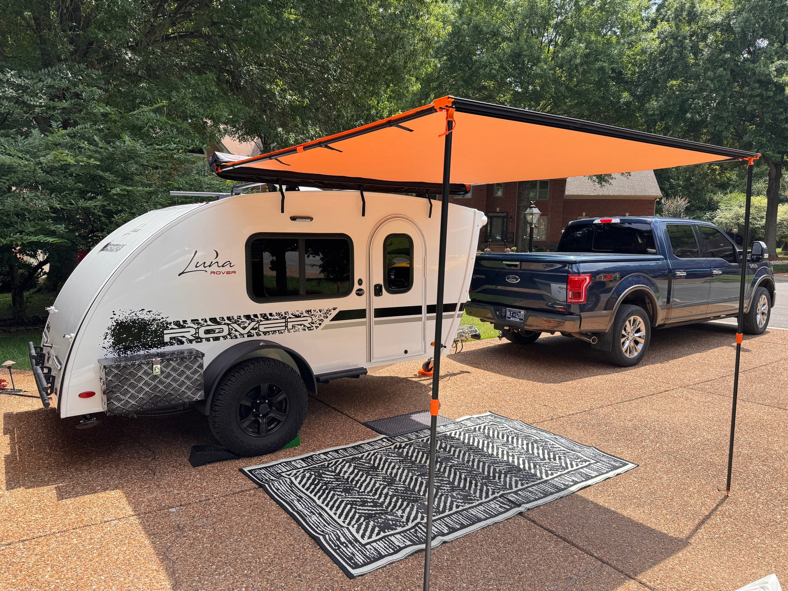 and canopy amidst green trees. Perfect for your next outdoor adventure!|White Luna Rover RV rental: close-up of side with window