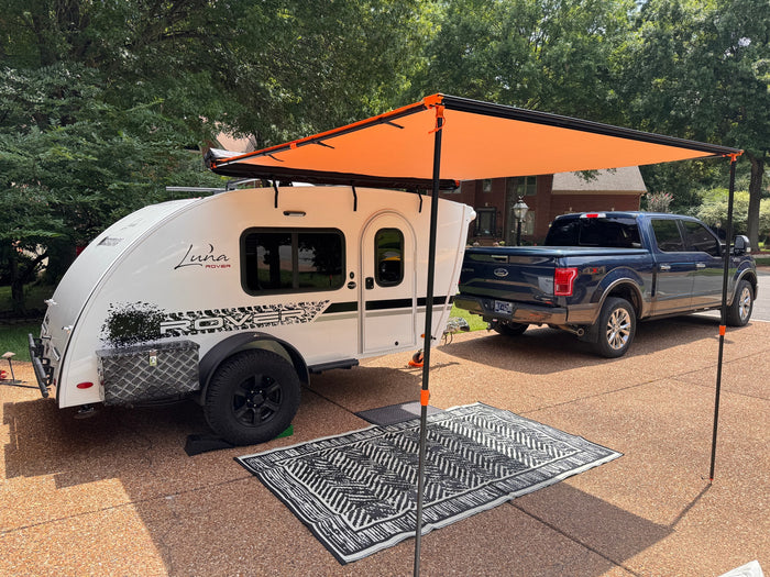 and canopy amidst green trees. Perfect for your next outdoor adventure!|White Luna Rover RV rental: close-up of side with window