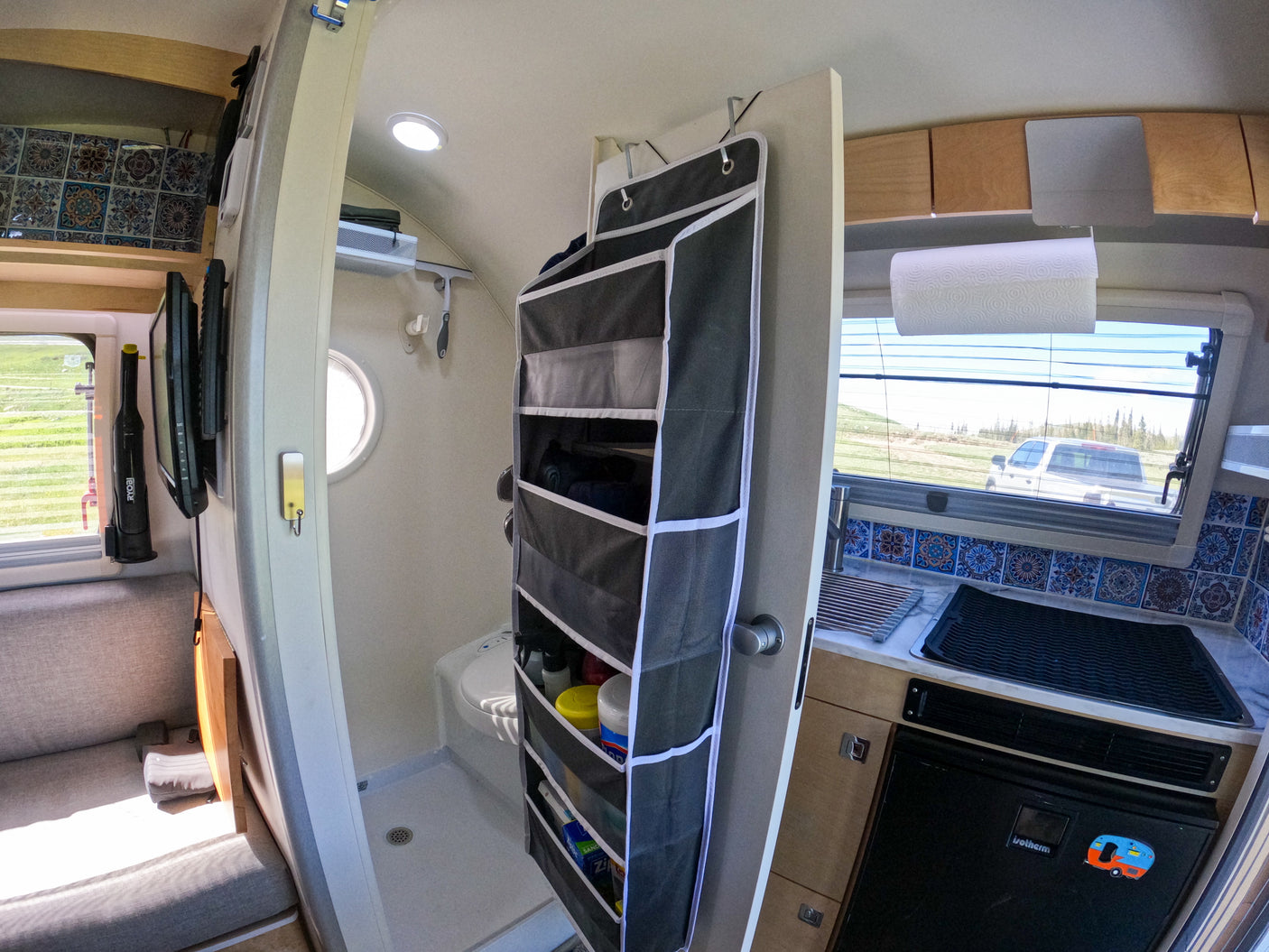 Inside a compact rv rental: efficient kitchen, wet bath with toilet, hanging storage, and mounted TV, maximizing small space.