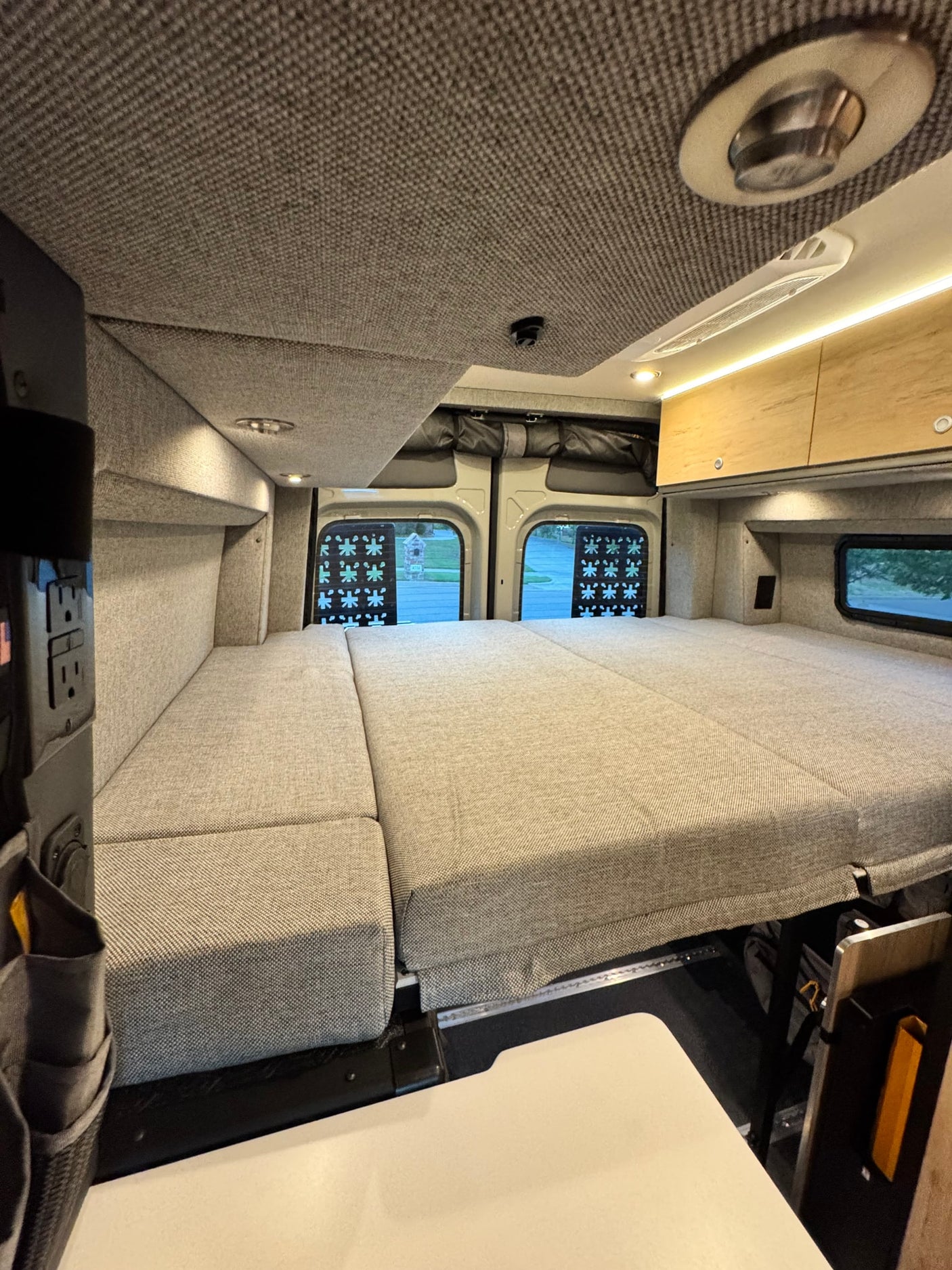 Relaxing RV rental interior with a spacious, modular bed, overhead storage, and ambient lighting.