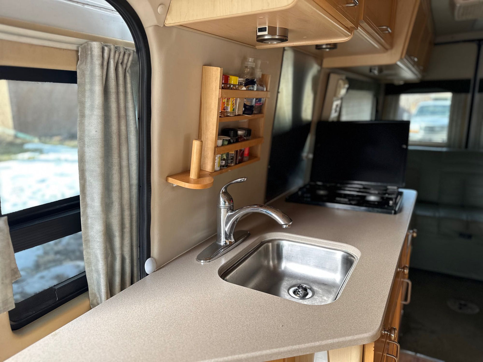 parked among green trees and hills.|White and green Leisure Travel Vans FreeSpirit 210B Class B RV parked on a street. Ideal for your next rv rental road trip.|White & green Leisure Travel FreeSpirit 210B camper van