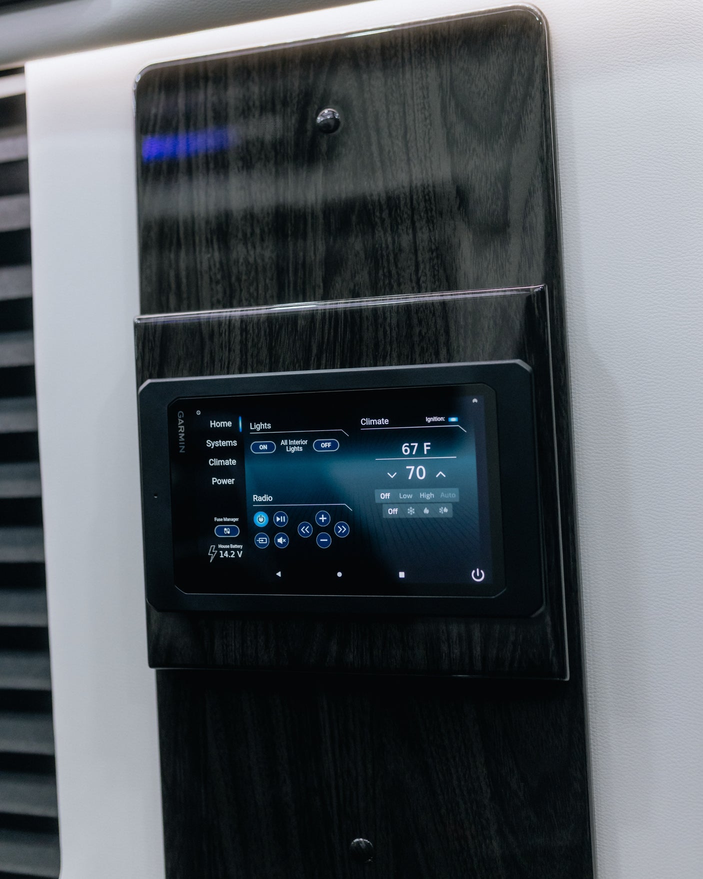 A Garmin RV control panel on a dark wood-grain wall, managing climate, lights, and radio. Perfect for an RV rental.