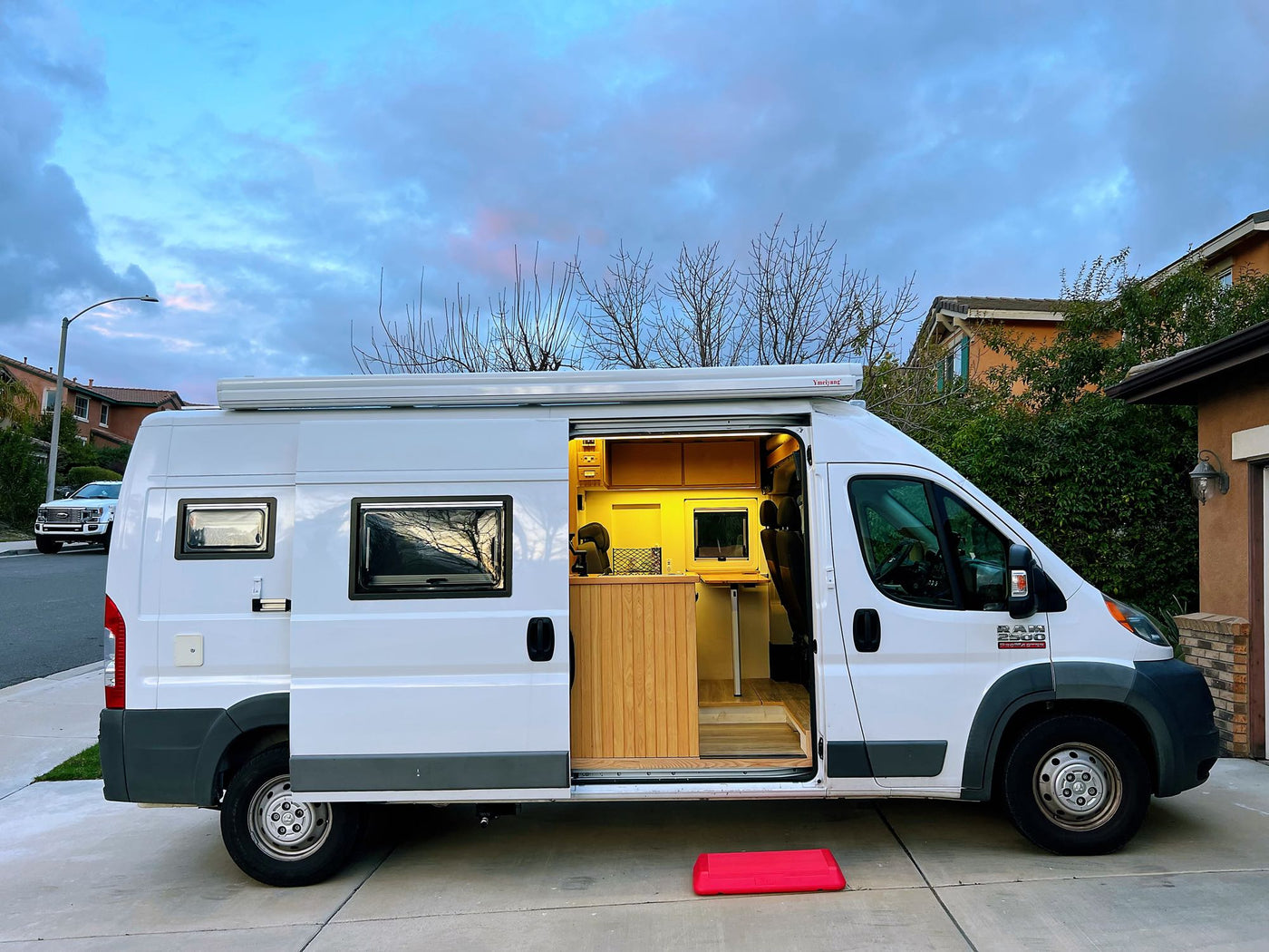 is at a Love's gas station at dusk. Person inside illuminated interior.|Experience van life! This white Ram ProMaster camper van — photo 4