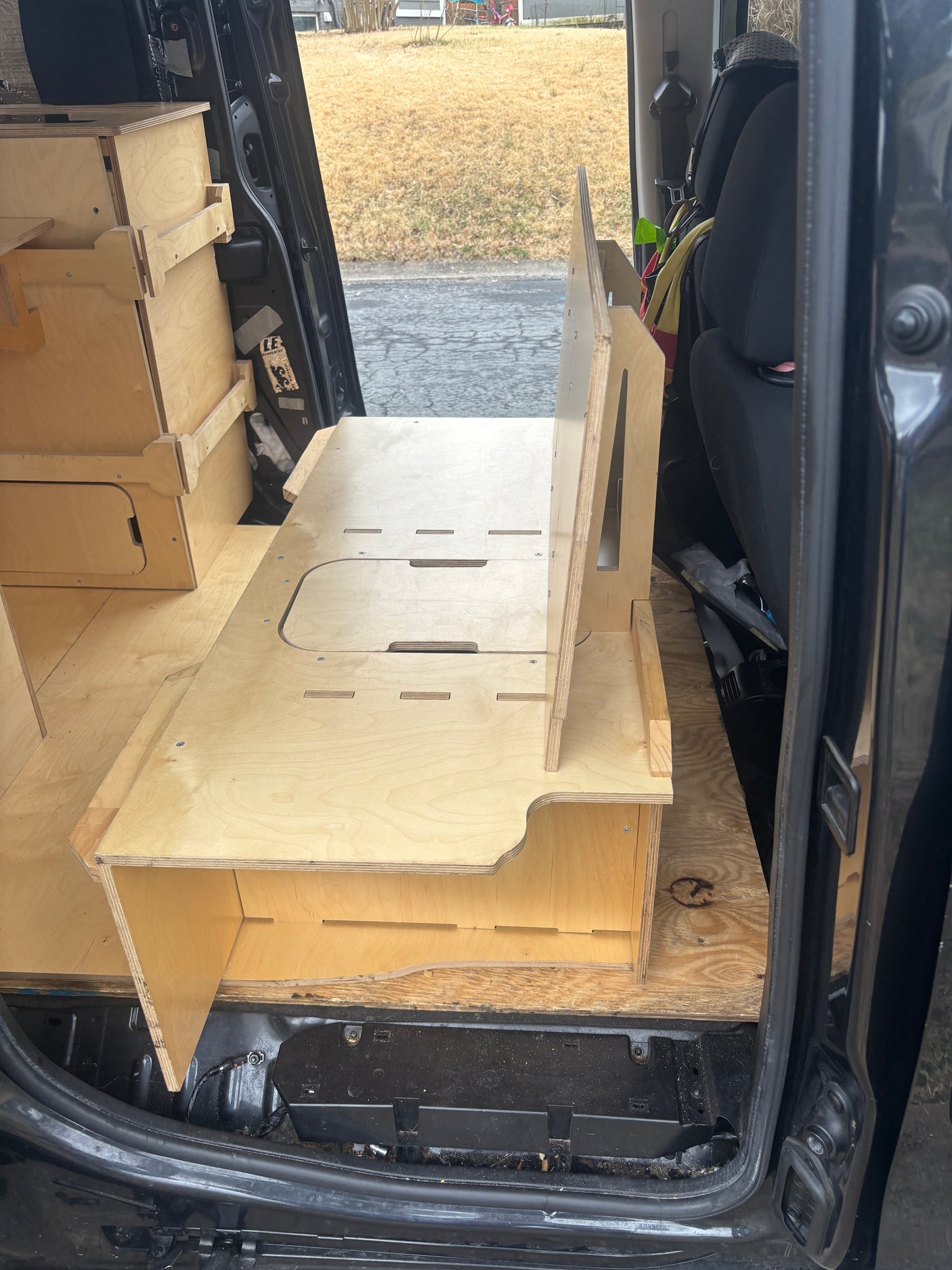 Custom modular wooden interior of an RV rental van, featuring clever storage units and sleeping platforms.