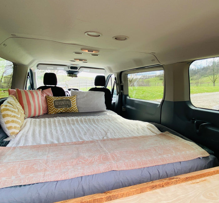 grassy field amidst scenic mountains.|Cozy RV rental camper van interior. Features comfortable benches