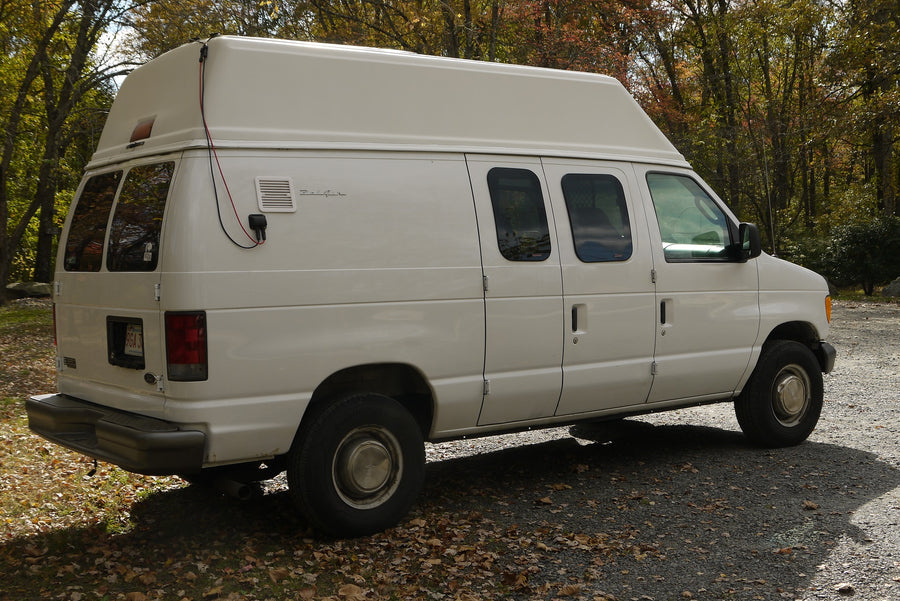 showcasing its classic lettering and surface reflections.|White Ford high-top van
