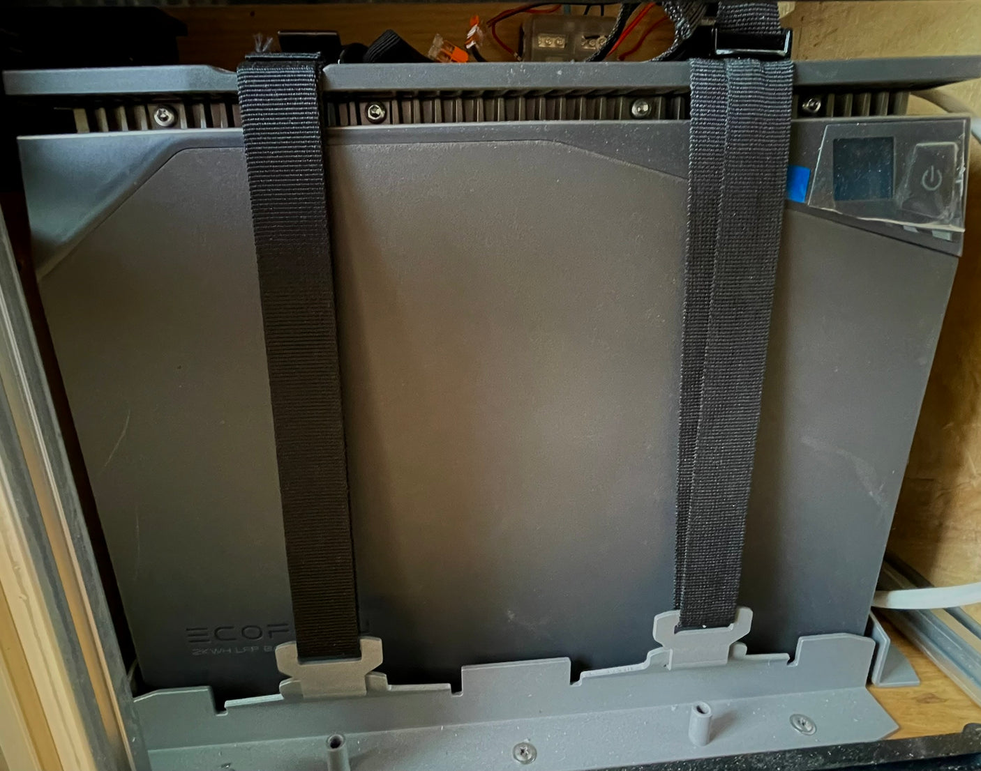 A dark gray EcoFlow 2KWH LFP battery secured with black straps. Ideal for off-grid RV rental adventures & portable power needs.