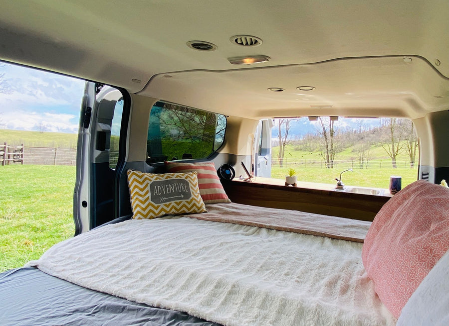 and cozy bed for travel adventures.|Custom-painted RV rental van featuring blue mountains and trees