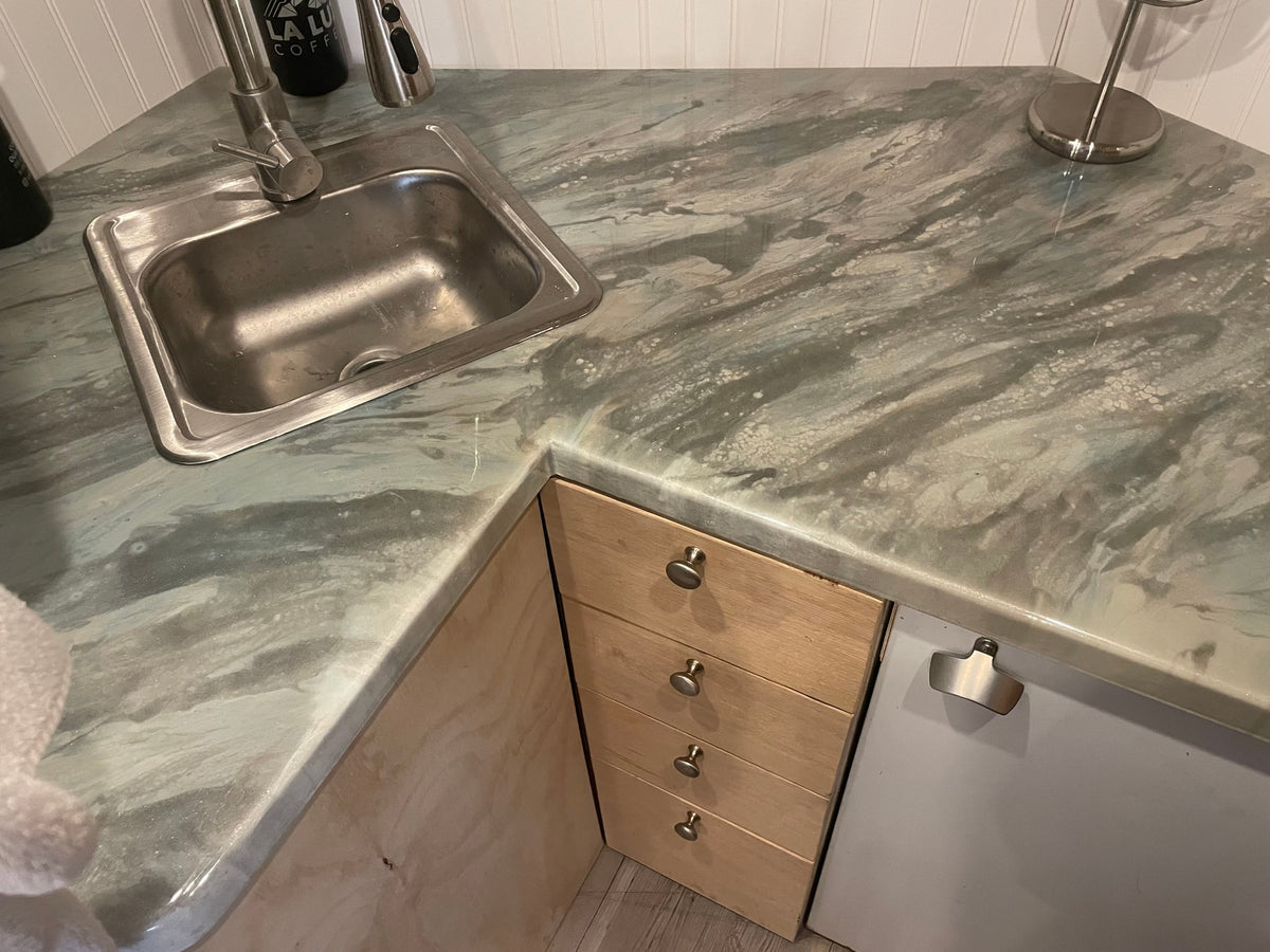 Inside an RV rental, a compact kitchen counter features a stainless steel sink, pull-down faucet, and a grey marbled countertop. — photo 3
