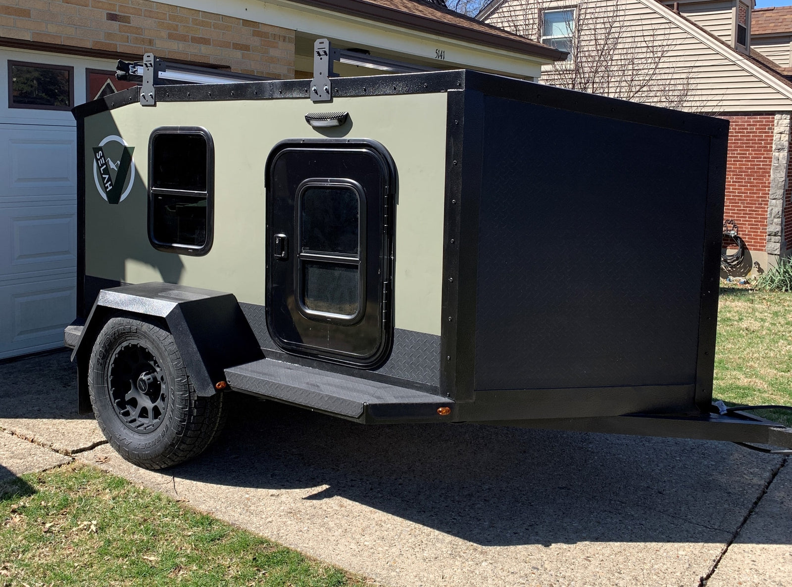 perfect for a road trip.|This compact green and black Selah adventure trailer is great for RV rental camping and off-road travel.|Perfect RV rental experience! A happy couple poses with their Selah camper and awning in a green forest.|Couple embraces their RV rental camper amidst a stunning autumn forest of red leaves. Bikes ready for adventure.|RV rental: Light wood interior with projector
