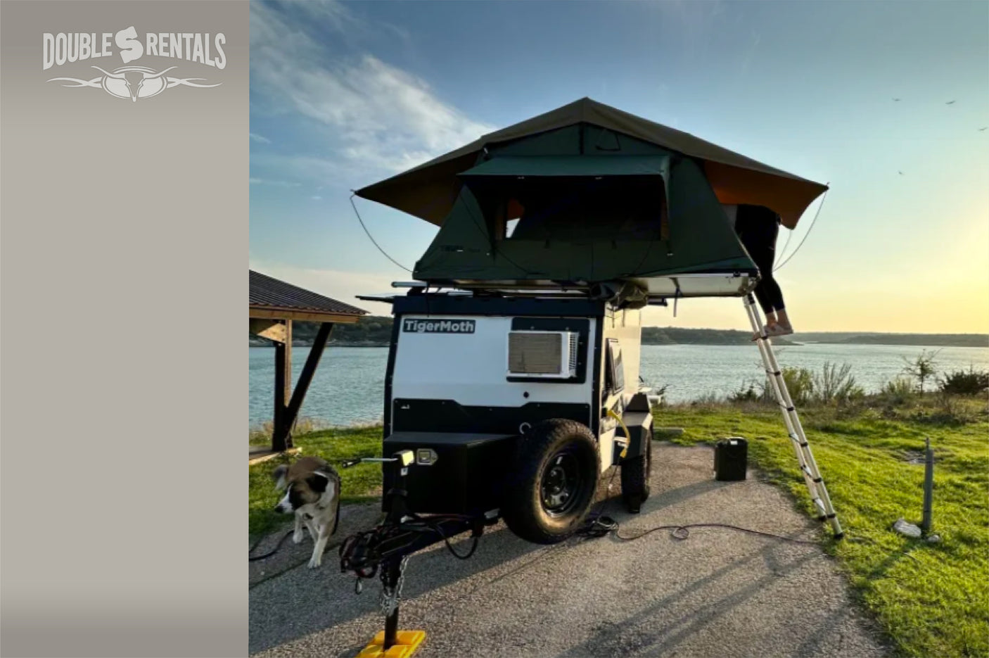 Our RV rental includes this TigerMoth camper with a rooftop tent by the lake at sunset, ready for your next adventure with your dog!