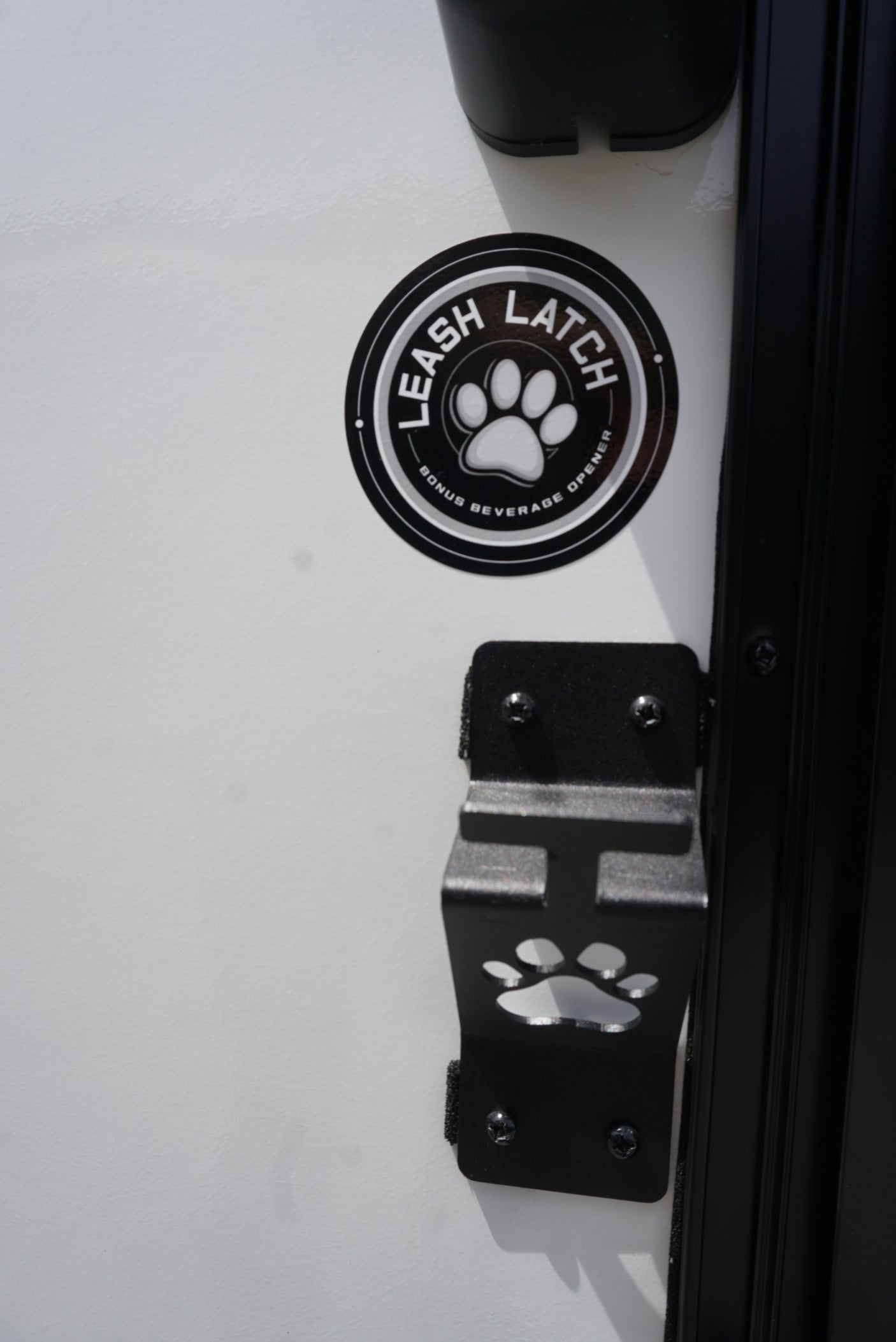 RV rental: Close-up of a "Leash Latch" paw print bracket & sticker, also a bonus beverage opener. Perfect for pet adventures.