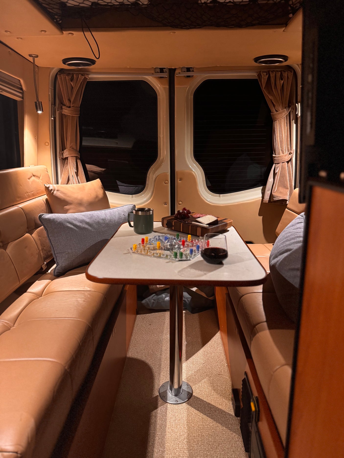 An inviting RV rental interior, showing a table set for a game, wine, and snacks between leather benches.