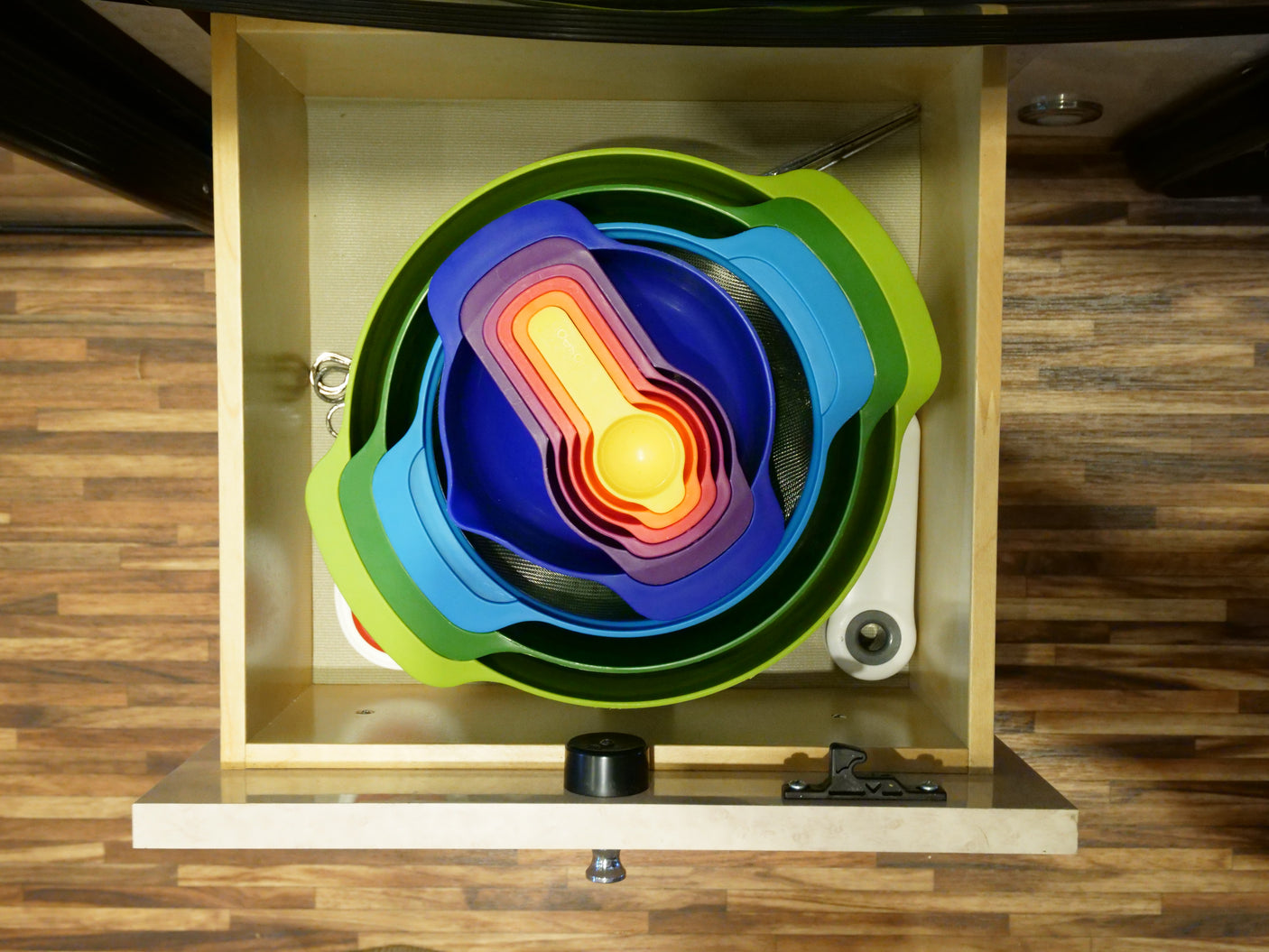 RV rental kitchen drawer with colorful nested measuring cups and bowls for compact storage.