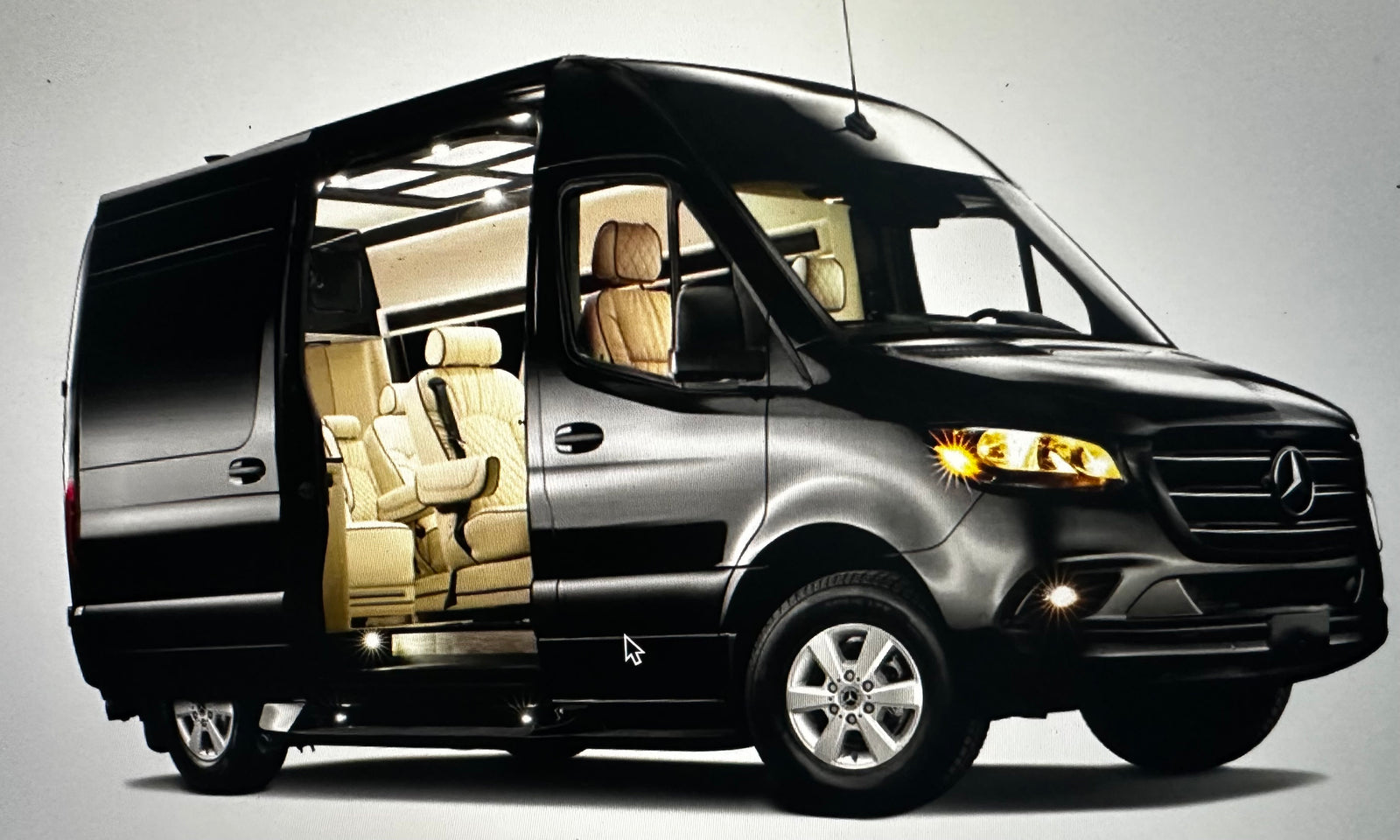 Black Mercedes-Benz Sprinter van with side door open revealing a luxurious tan interior