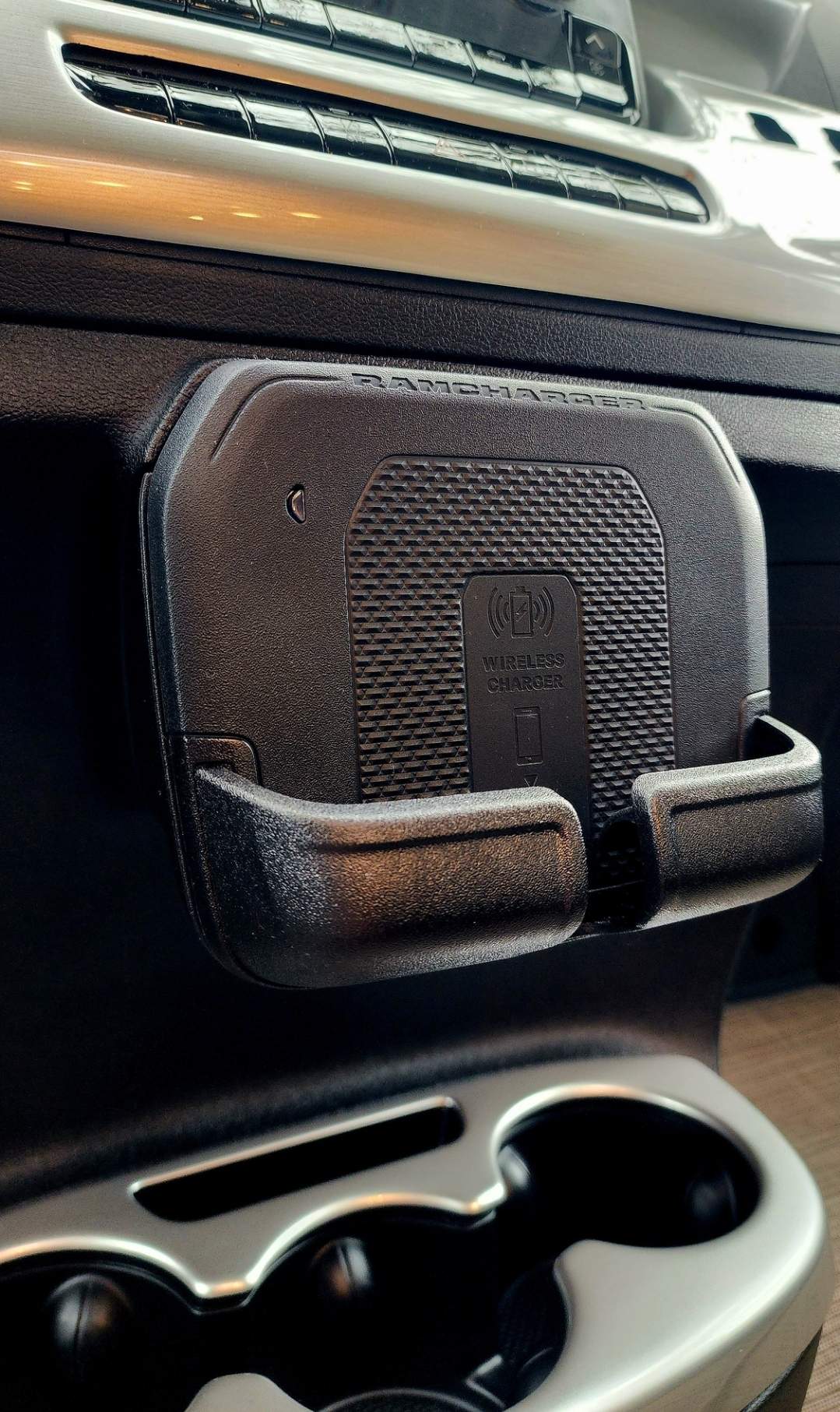 Close-up of a black RAMCHARGER wireless phone charger/holder mounted below dash controls in an RV rental.