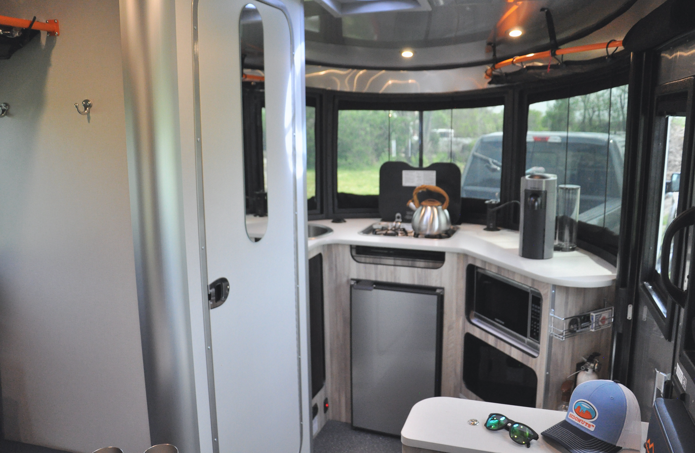 This rv rental showcases a compact kitchen with a stove, fridge, and microwave, ready for your next road trip adventure.