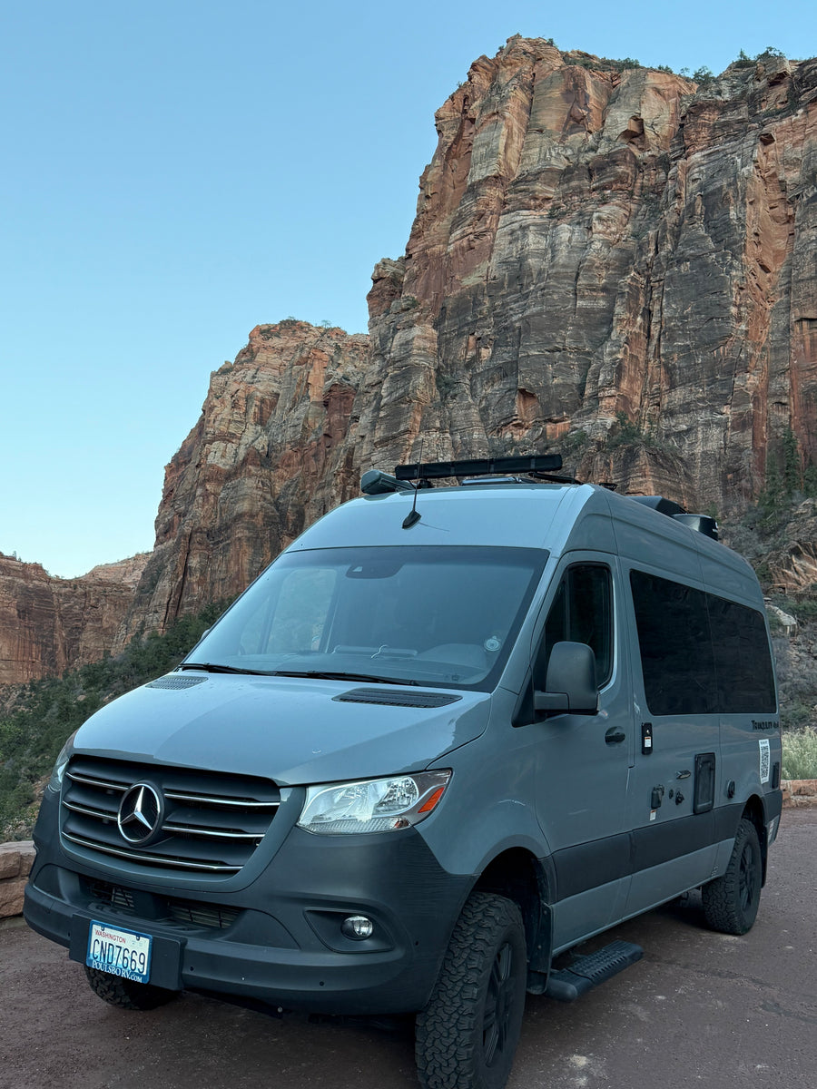 Adventure awaits with this sleek grey Mercedes Sprinter RV rental, parked against stunning red rock mountains.