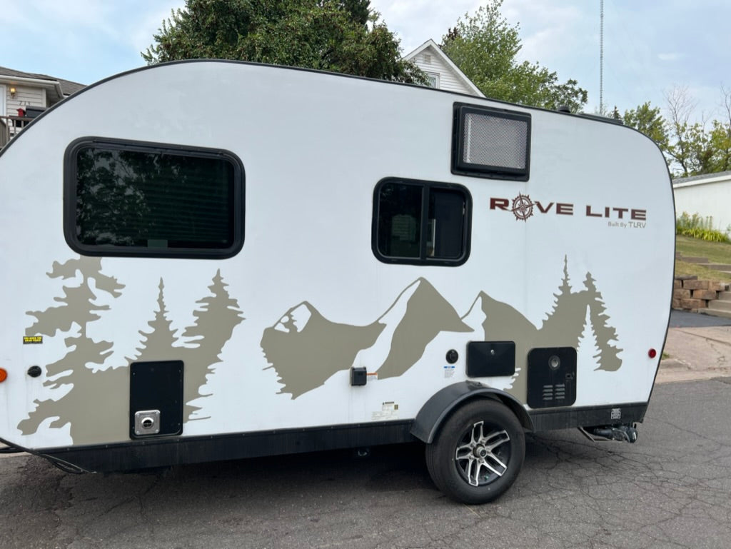 White Rove Lite travel trailer, ideal for an RV rental, features mountain & tree graphics.