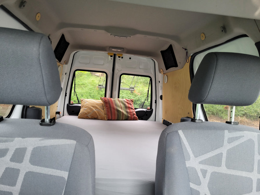 Cozy camper van interior with a bed and pillows, ready for adventure. Ideal for your next RV rental road trip or van life.