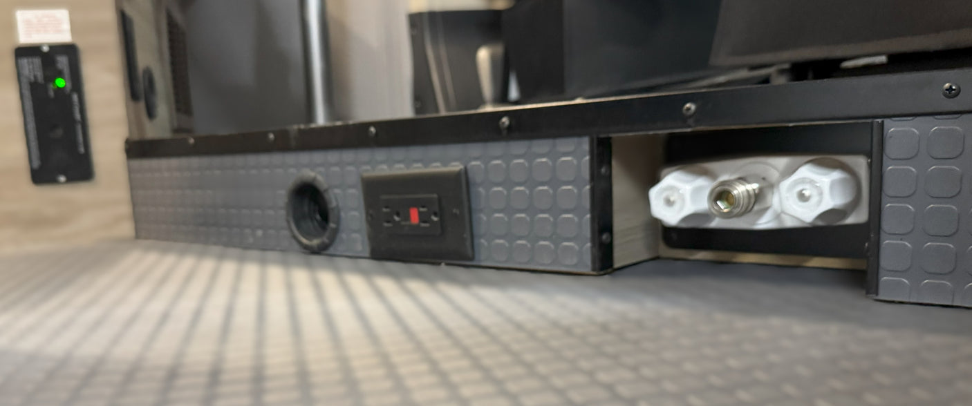 RV rental: Closeup of an interior utility panel with a GFCI outlet, water connections, and power status light.