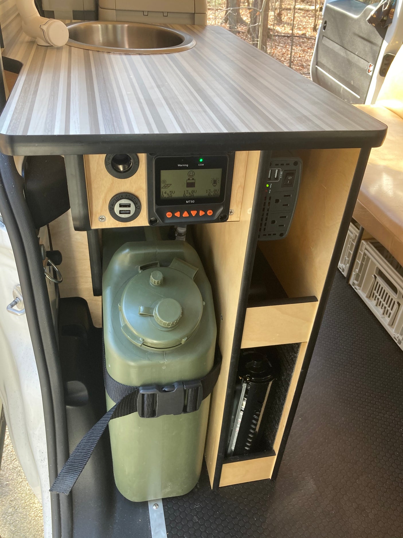 RV rental utility setup: compact sink, solar charge controller (MT50), USB/AC power outlets, and a large water jug.