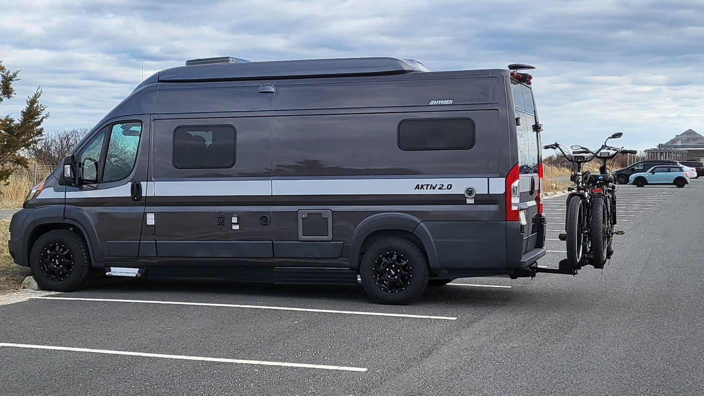 A stylish dark grey Hymer Aktiv 2.0 camper van, an ideal rv rental, with bikes on the back for your next adventure.