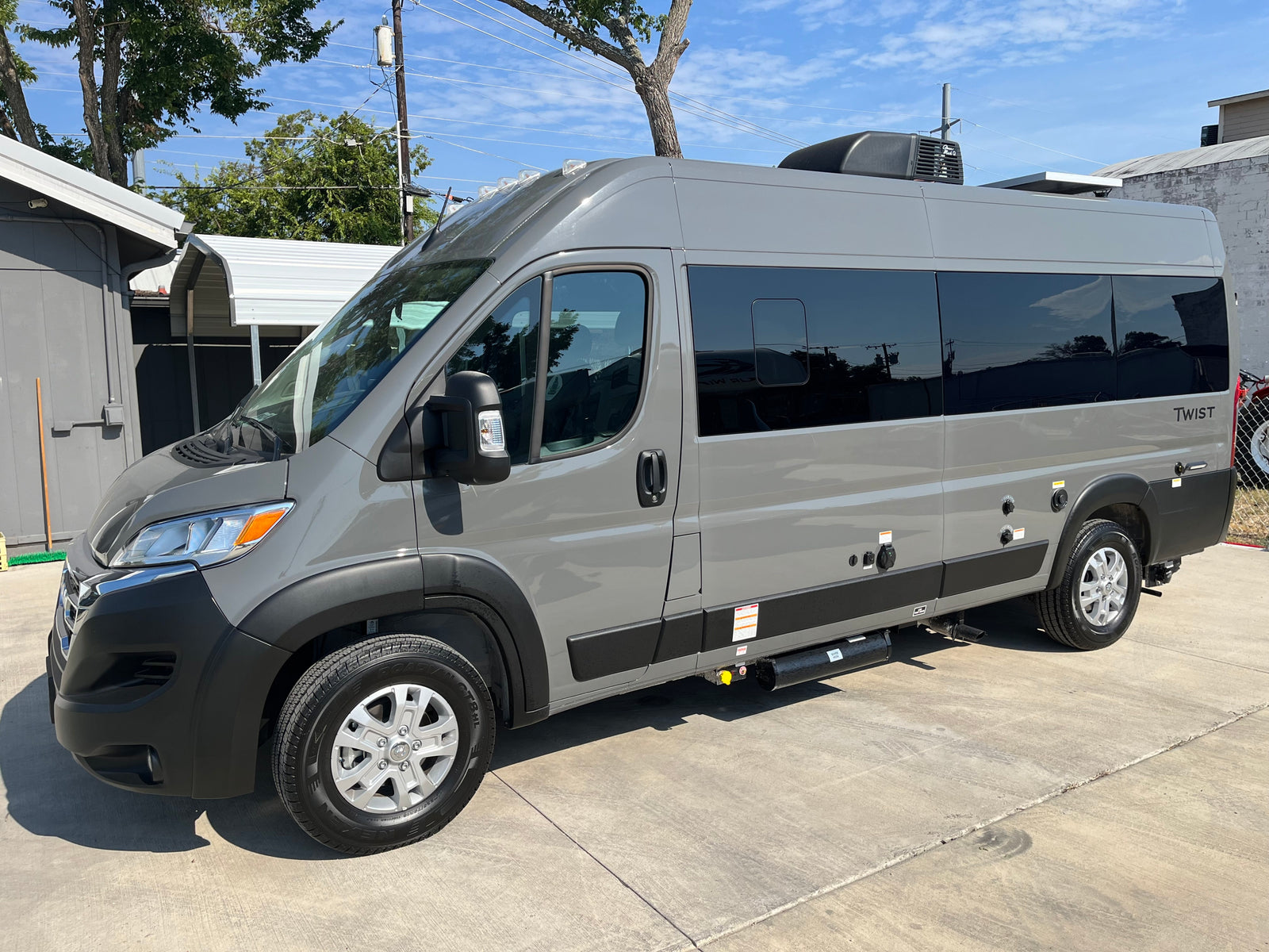 Gray Class B rv rental, a modern camper van, parked outdoors on concrete, perfect for travel adventures.