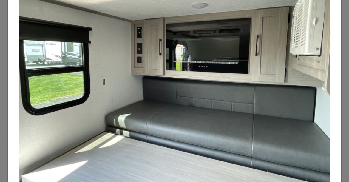 set against a forest backdrop.|RV rental interior featuring a dark gray seating area