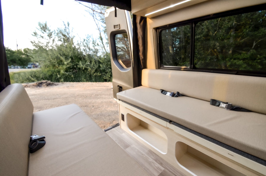 and a glimpse of the compact bathroom.|Explore this modern RV rental interior featuring a functional kitchen with sink