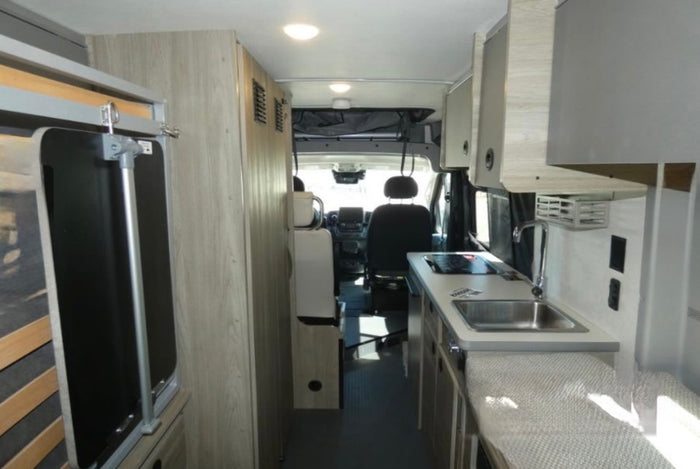 mountains and lake reflecting sunset.|RV rental camper van interior. Features a compact kitchen with sink/stove