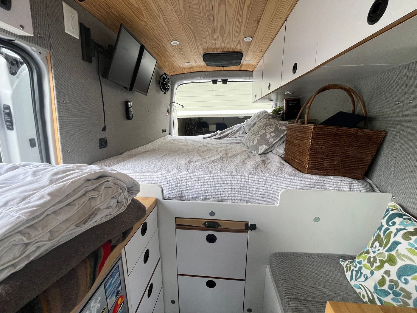 Inside a bright RV rental camper van: full bed, wood-paneled ceiling, and smart storage for your adventures. — photo 11
