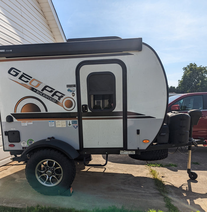 A Geo Pro Rockwood travel trailer, perfect for an rv rental, is parked outdoors on a sunny day.