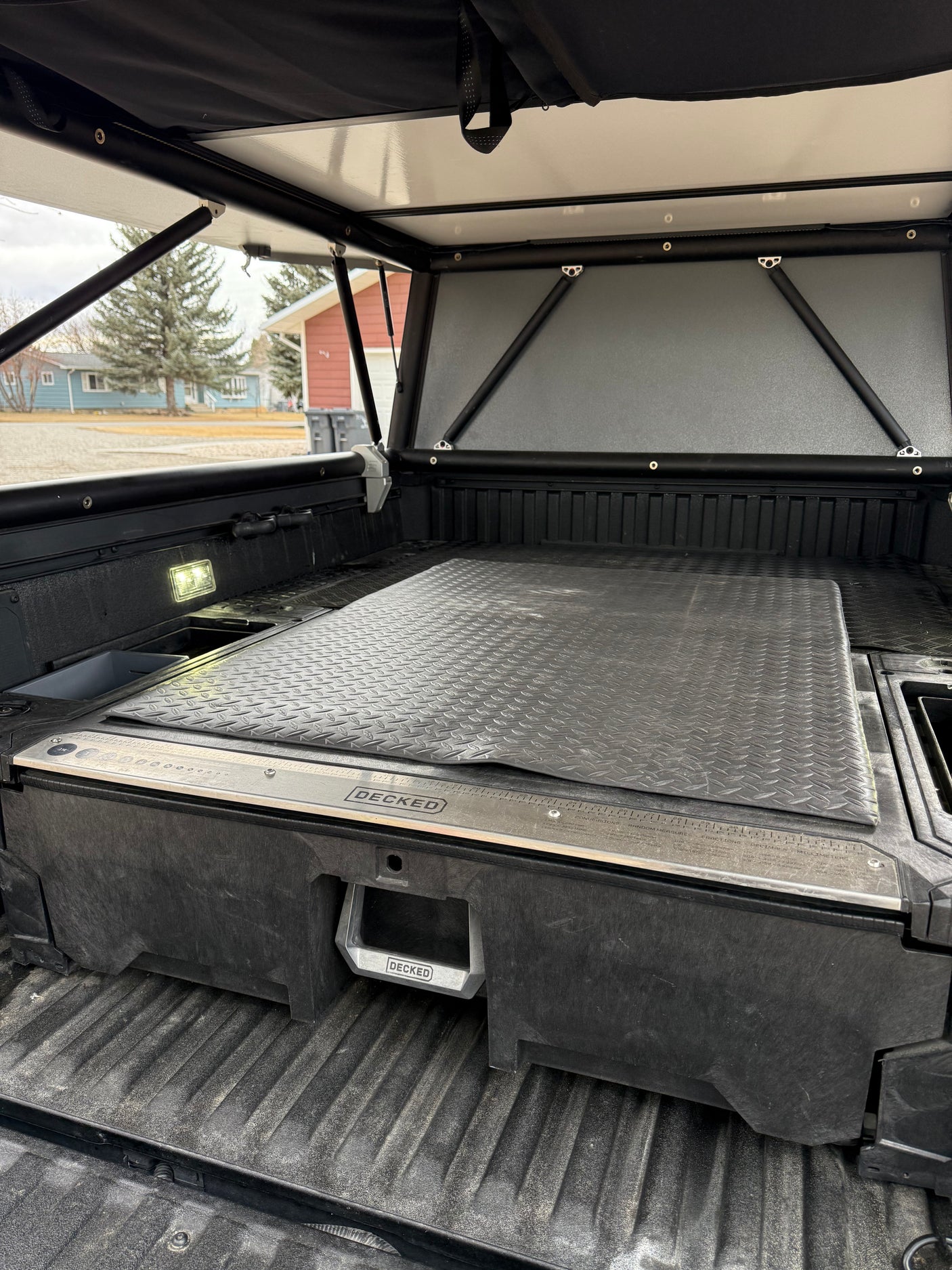Truck bed setup with a DECKED drawer system and open pop-up camper top. Perfect for RV rental trips & overlanding adventures.