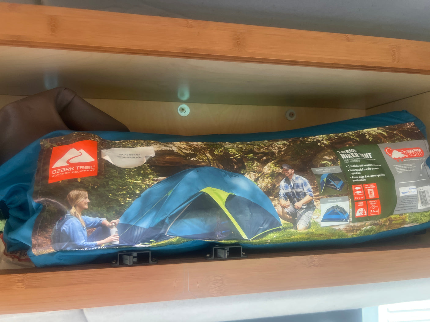 Packaged Ozark Trail 2-person hiker tent, ideal for RV rental camping, neatly stored on a wooden shelf.