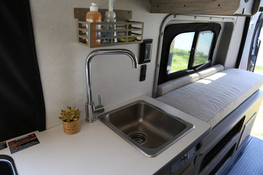 Compact RV rental kitchen with sink, faucet, and storage, ideal for road trips and small space living.