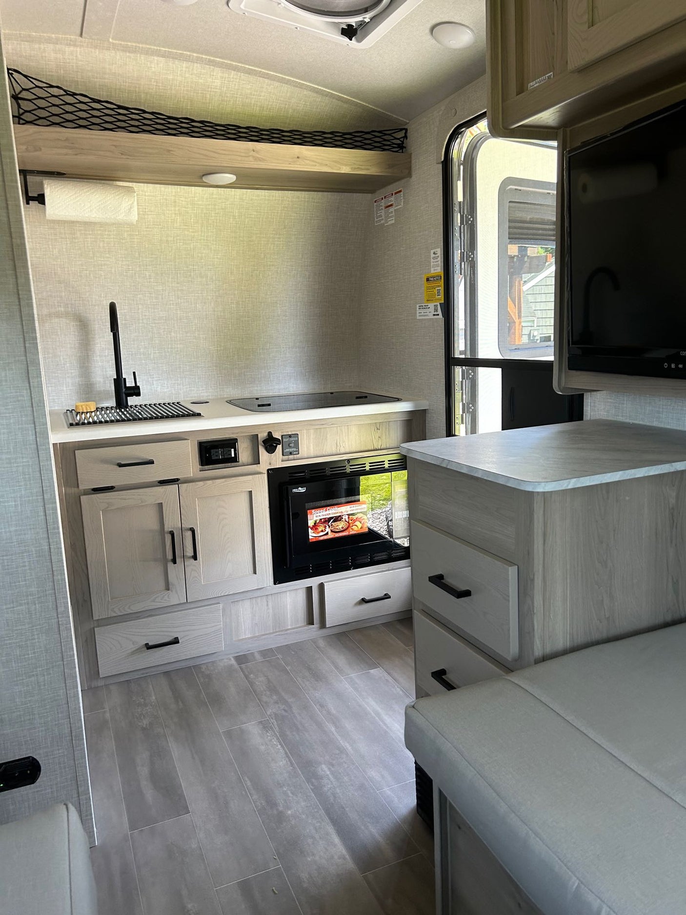 with a fire pit & chair on a gravel patio.|Step inside this compact RV rental's modern kitchen with sink