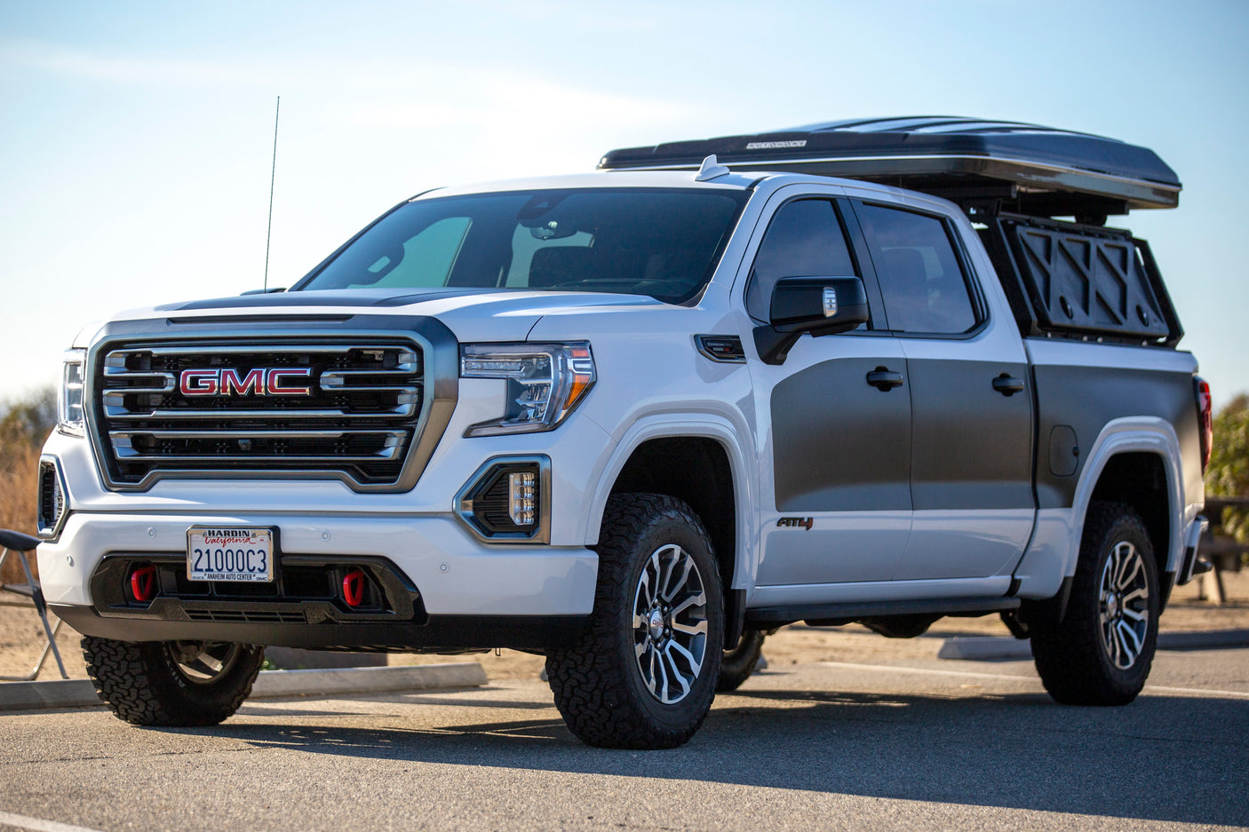 Overlanding-ready white GMC Sierra AT4 truck with rooftop tent. Explore via this versatile RV rental.