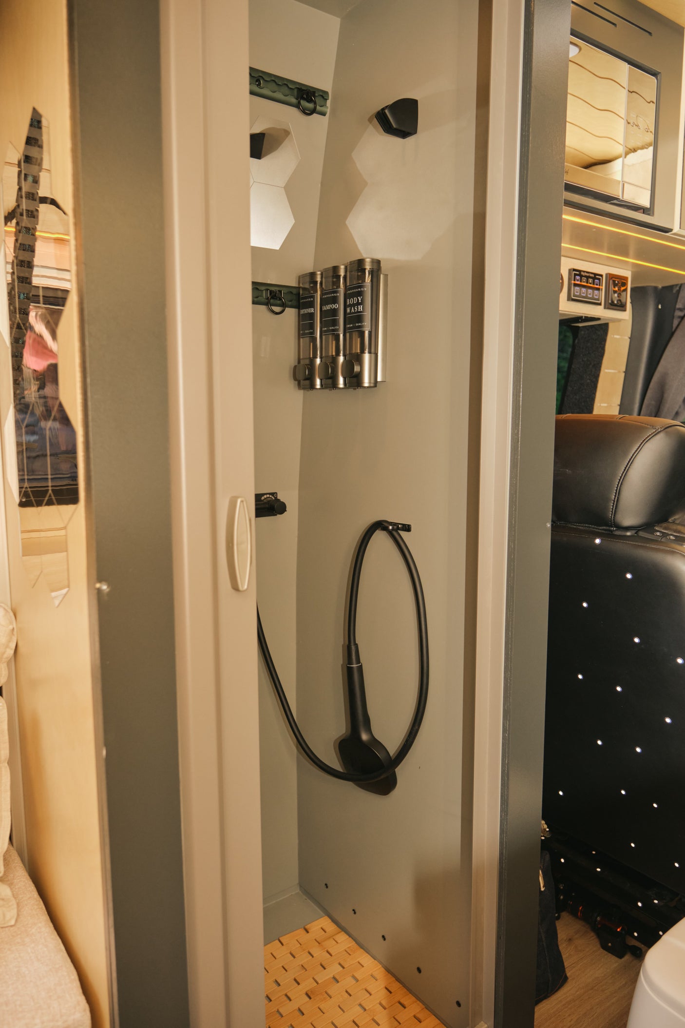 Compact shower with essential amenities like wall-mounted dispensers and a handheld shower in an RV rental.