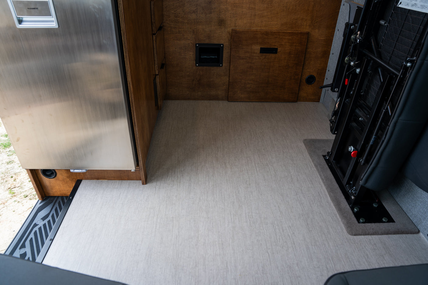 An RV rental's practical interior: Dometic fridge, custom wood storage, and versatile passenger seating.