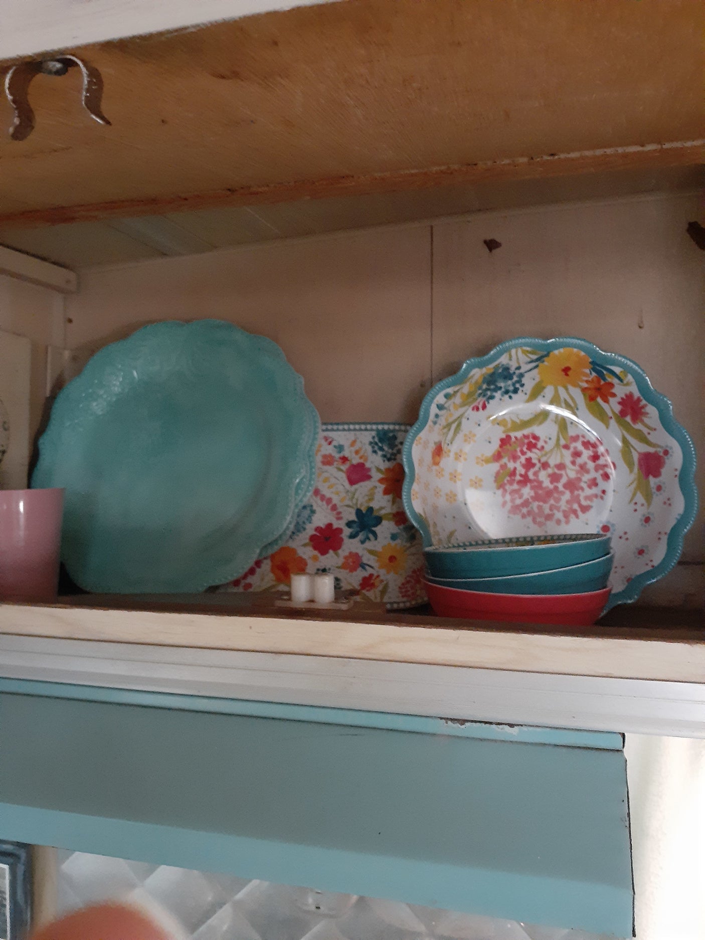 Colorful dishes in a wooden rv rental cabinet, perfect for camping kitchen needs.