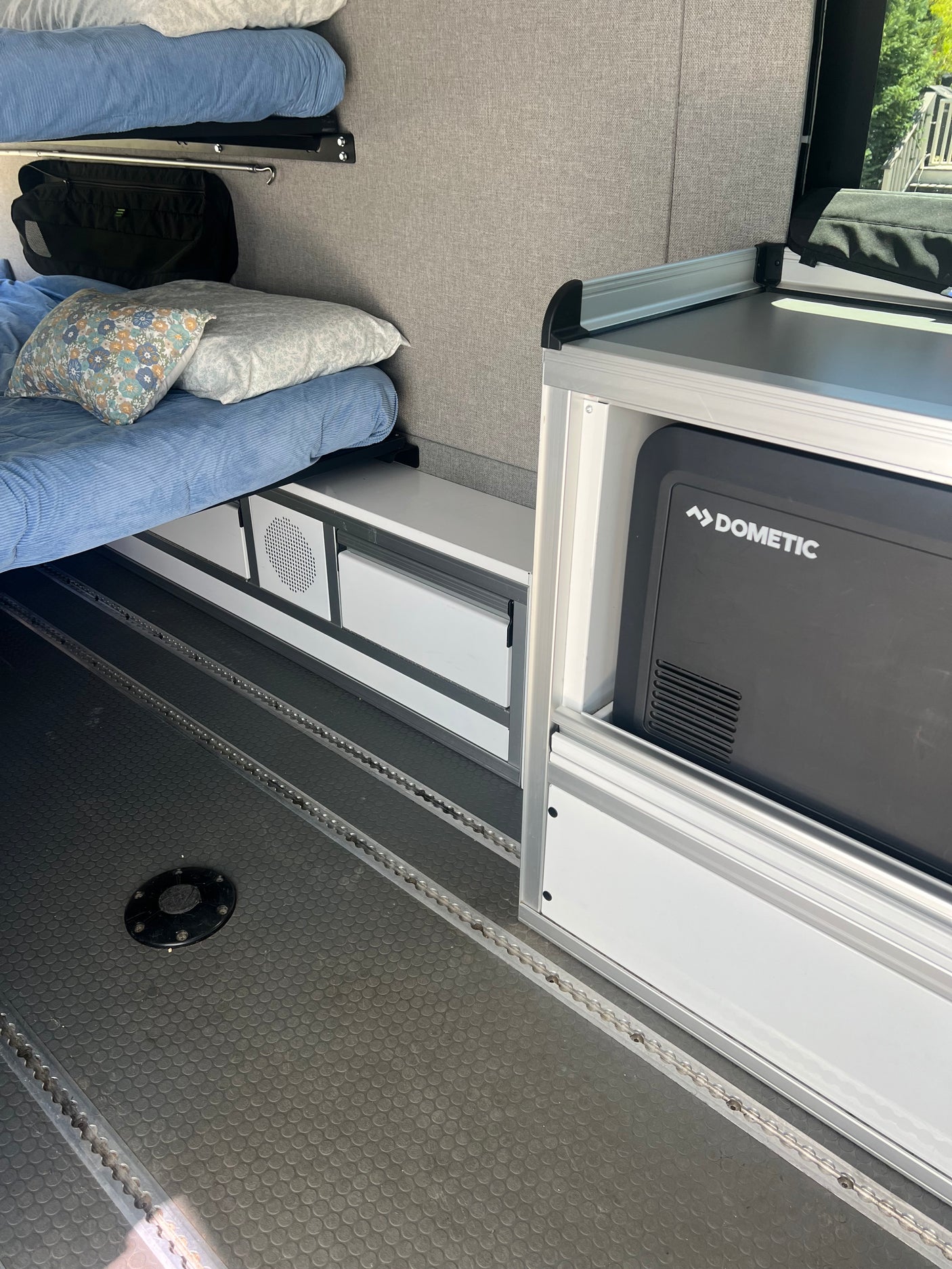 RV rental: Camper interior showcasing bunk beds, integrated storage, and a Dometic fridge on textured L-track flooring.