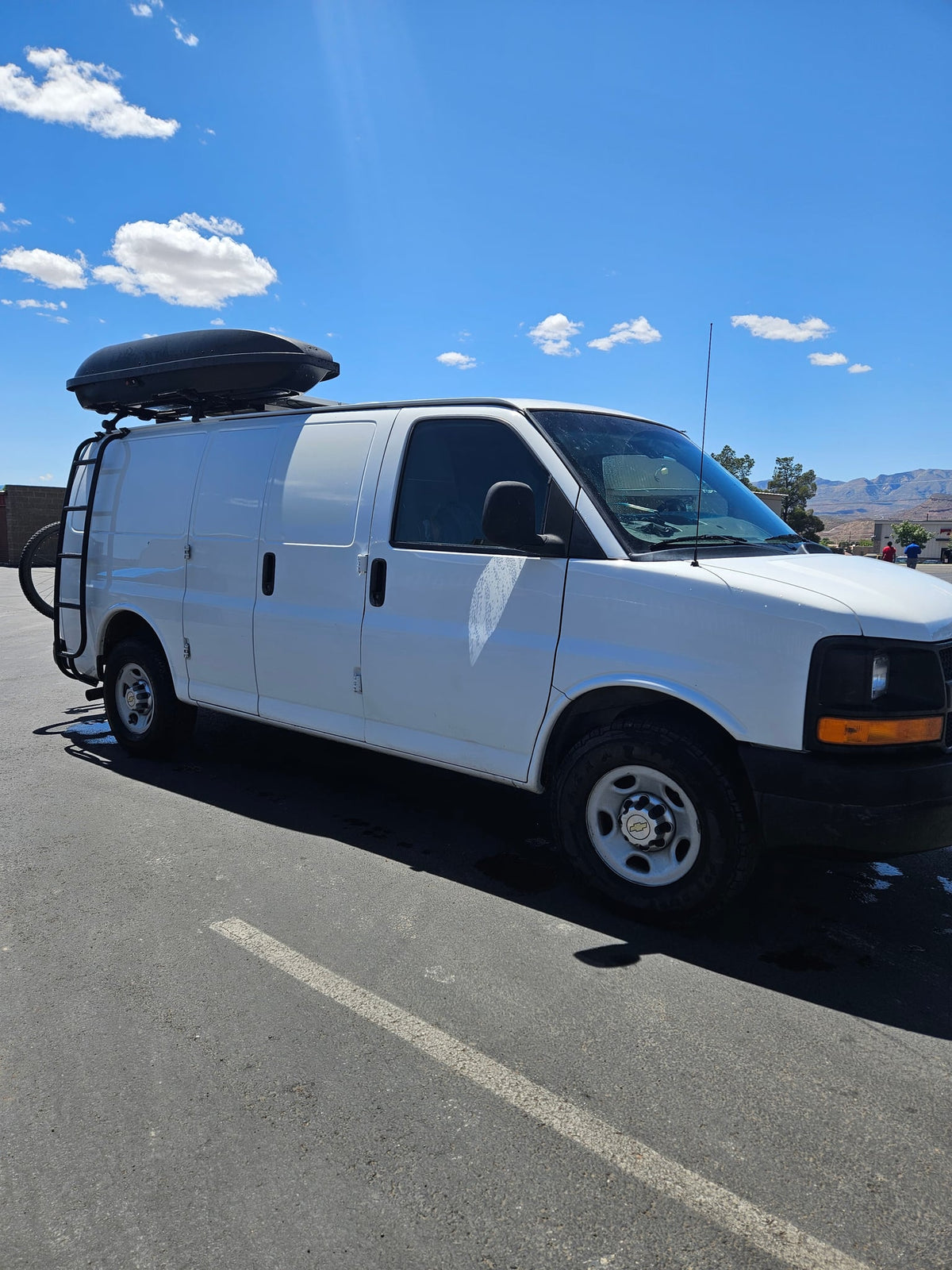 parked outdoors amidst tall pine trees under sunny skies.|This RV rental offers a cozy camper van interior — photo 11